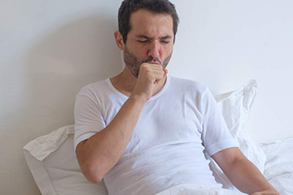 男子躺在床上和咳嗽。