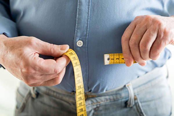 Overweight man measuring his waistline.