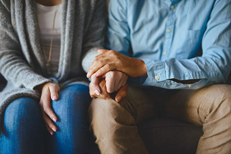 Husband and wife holding hands for support.