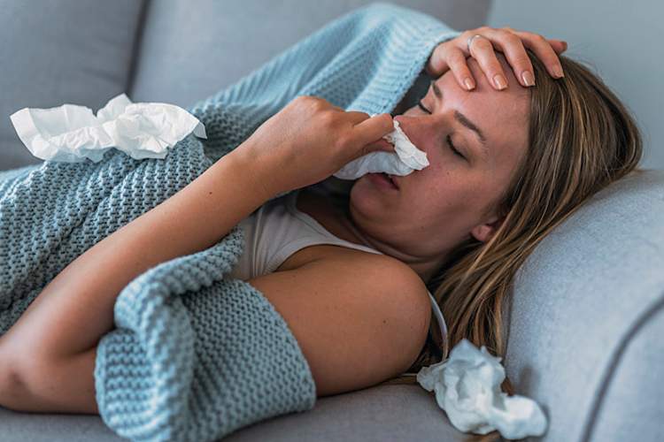 一个患流感的女人躺在家里的沙发上