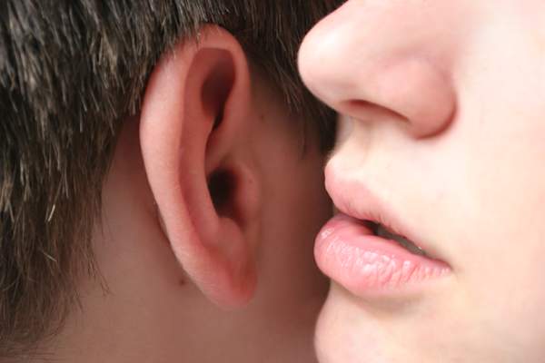 女人的嘴唇耳语到人的耳朵