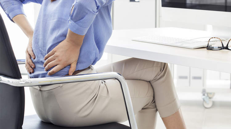 女性腰痛的工作坐在椅子上。