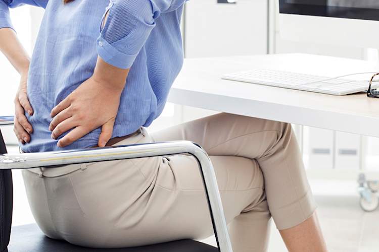 女性腰痛的工作坐在椅子上。