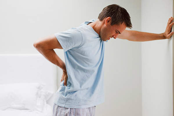 一个背部疼痛的人靠在墙上。