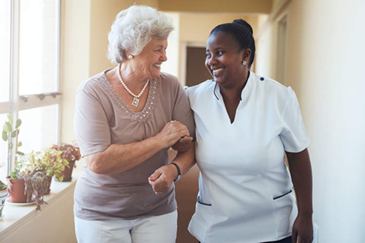 微笑的居家护理员和老年妇女走在一起