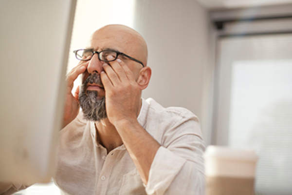 疲惫的人揉着眼睛坐在电脑前。