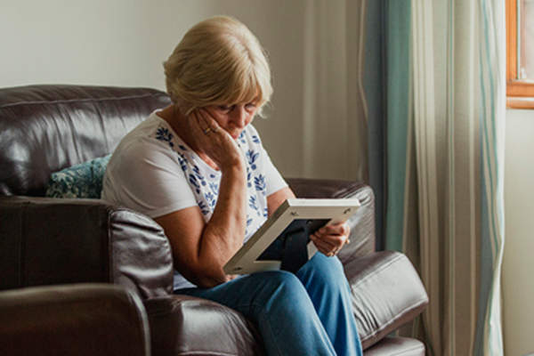 悲伤的女人看着已故亲人的照片。
