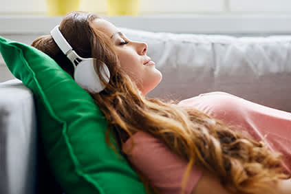 女人躺在沙发上听音乐。