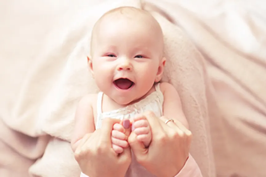 微笑的婴孩关闭与母亲的手。