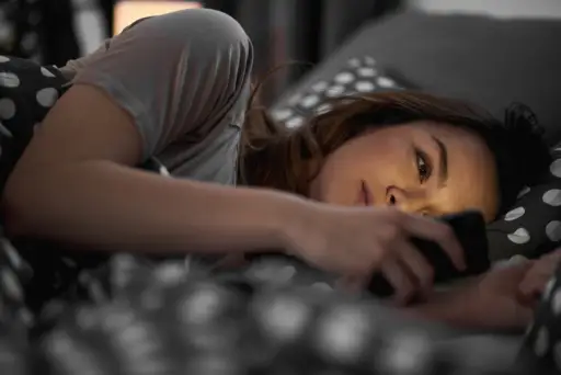 一个躺在床上看手机的年轻女人