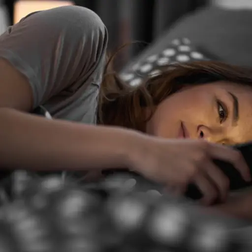 一个躺在床上看手机的年轻女人