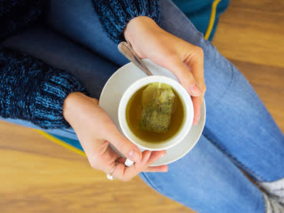女人与绿色的一杯茶。