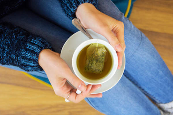 女人与绿色的一杯茶。