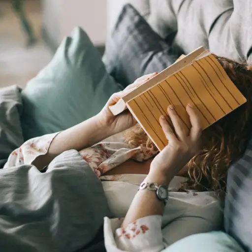 疲惫的女人在床上用书盖着脸