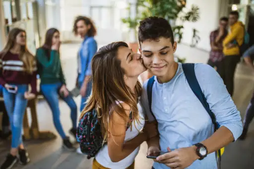 青少年的夫妇在走廊脸颊亲吻在学校