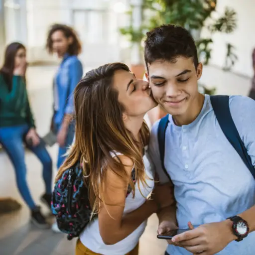 青少年的夫妇在走廊脸颊亲吻在学校