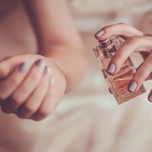 在手腕上喷洒香水的妇女。