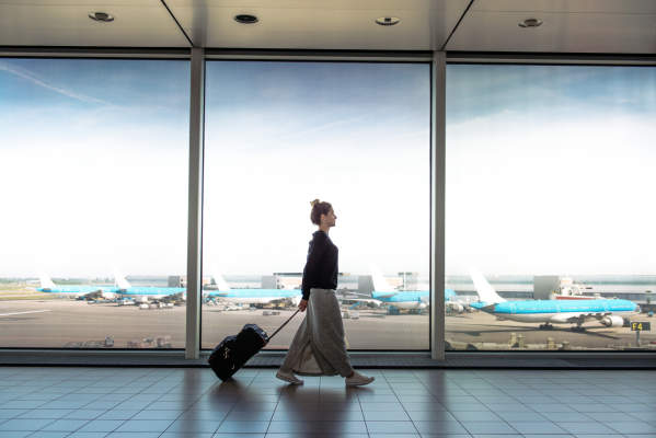 女人滚动手提箱走在机场候机时