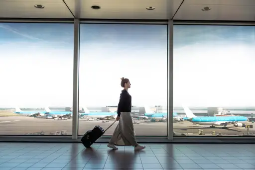 一位妇女推着行李箱走在机场候机厅