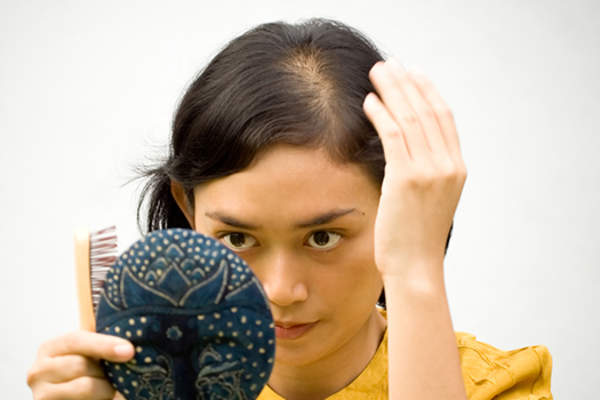 女人照镜子担心自己的脱发形象。