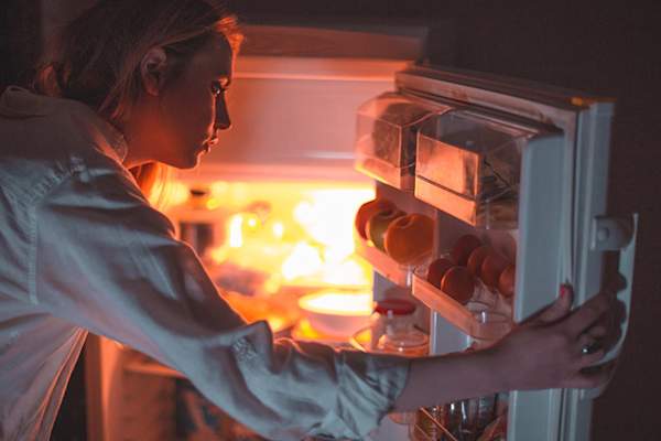 女人在晚上看在冰箱里。