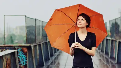 女人在雨中撑着一把雨伞。