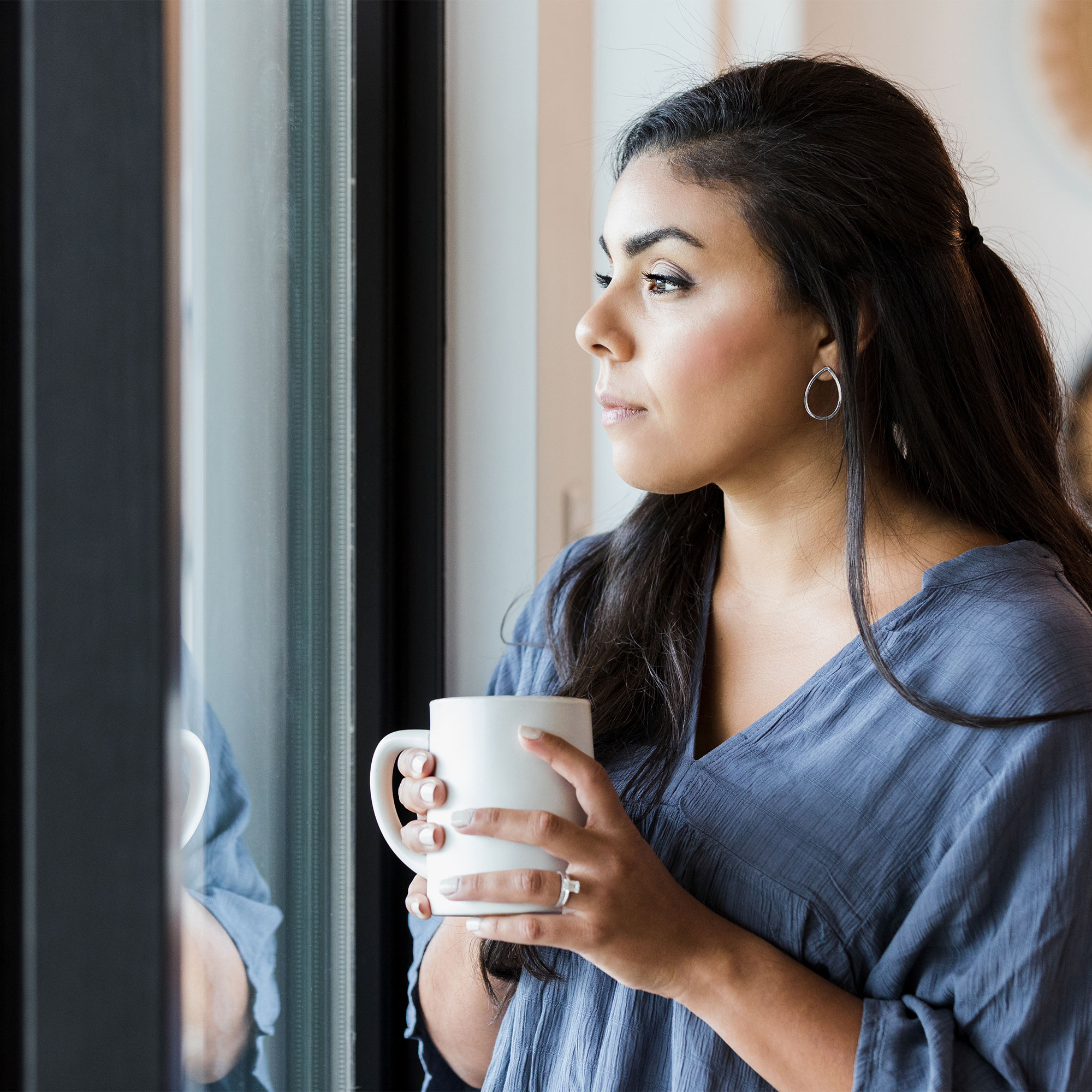 一个女人拿着杯子，看着窗外