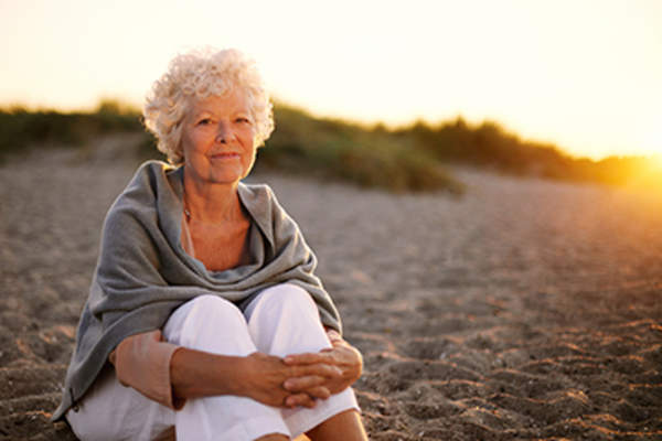 高级女子坐在沙滩上。