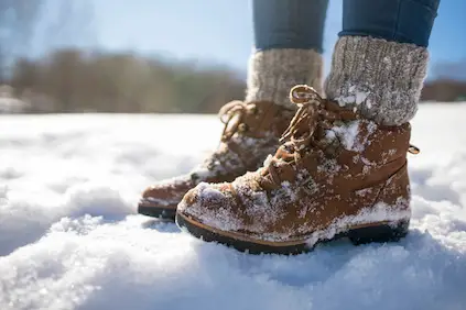 妇女佩带的冬天起动和蓬松袜子在雪。