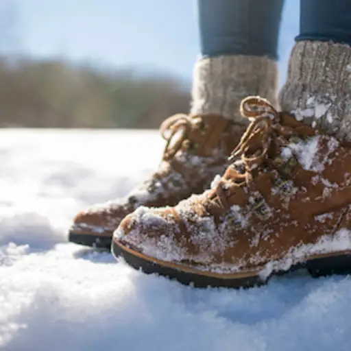 妇女佩带的冬天起动和蓬松袜子在雪。