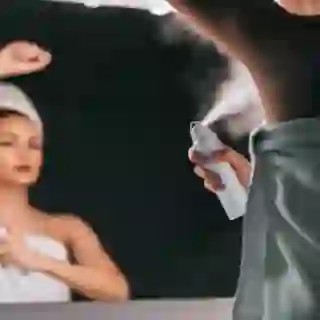woman using spray deodorant