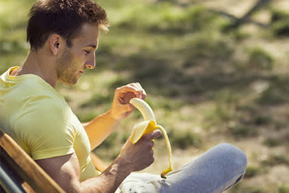 男子坐在外面晒太阳，剥香蕉。
