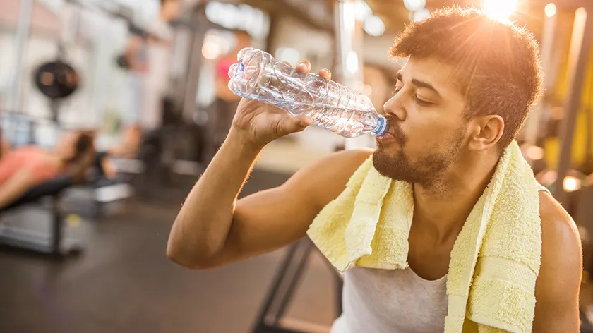 在健身房喝水的男人。