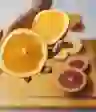 一个女人拿着一个橘子在砧板上