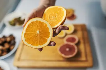 一个女人在砧板上举着一个橘子