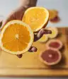一个女人在切菜板上举着一个橘子