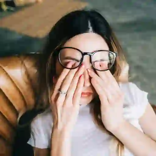 年轻女子戴着眼镜揉眼睛。