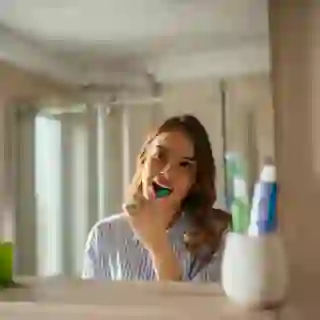 Young woman brushing her teeth in the mirror