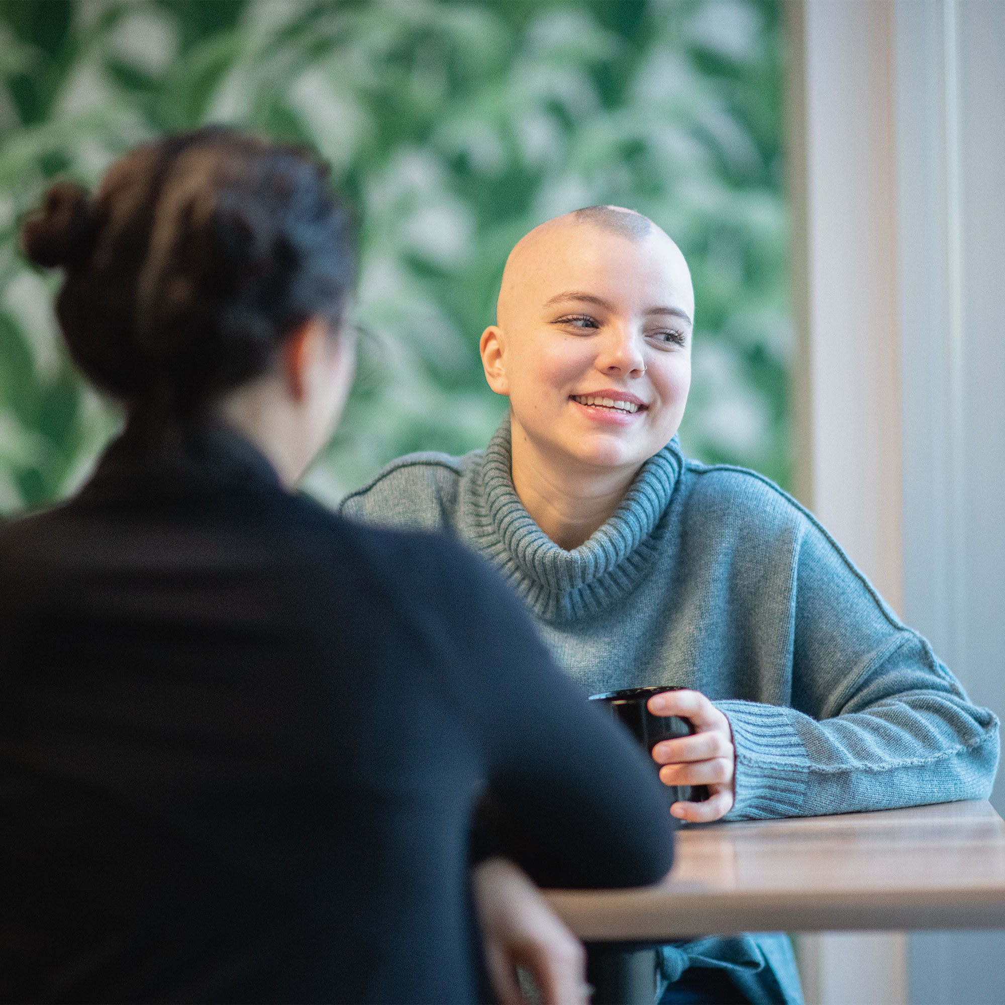 一个秃顶的女人和朋友喝咖啡