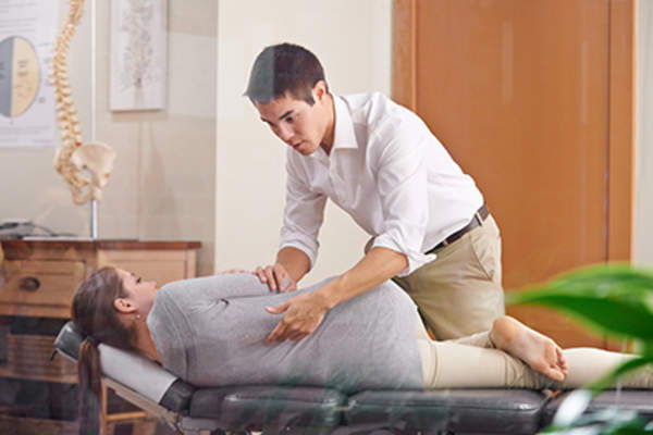 指压按摩师调整妇女的脊椎。