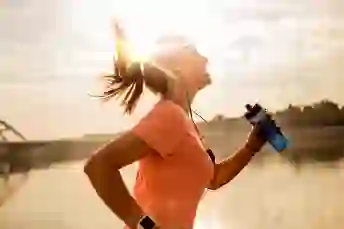 一个快乐的女人拿着水瓶时在外面跑到外面