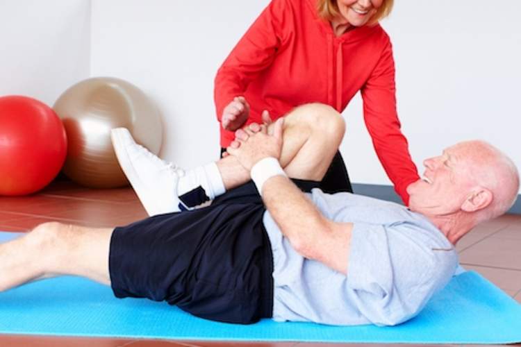 一位上了年纪的男子与理疗师一起治疗背痛。