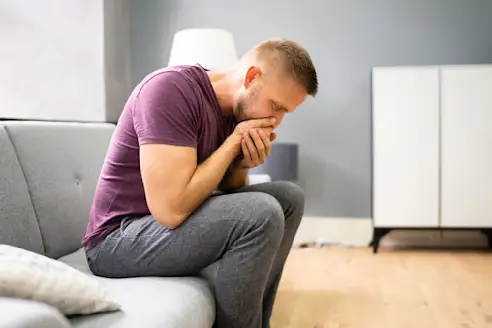 A nauseated man holds his hands over his mouth