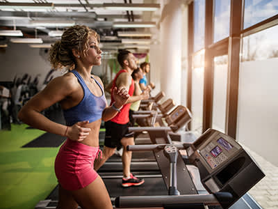 人们在健身房的跑步机上锻炼。