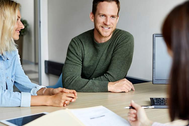 一对微笑的年轻夫妇正在和医生做笔记。