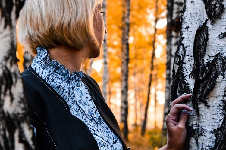 秋天,一位中年妇女站在树旁