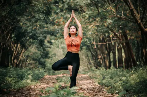 做瑜伽树姿势的少妇在森林里