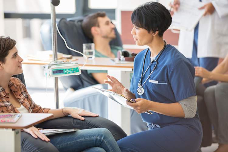 年轻女子在接受输液治疗时与医生交谈