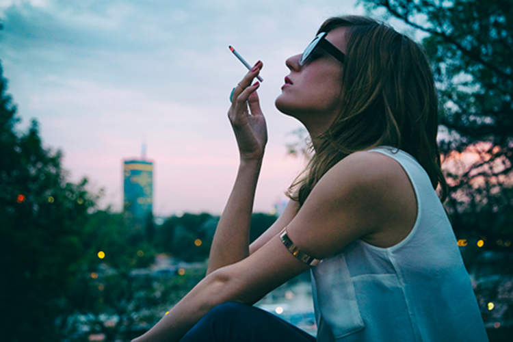 时髦的女人吸烟香烟户外