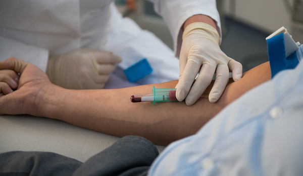 Nurse drawing blood sample from patient for testing.